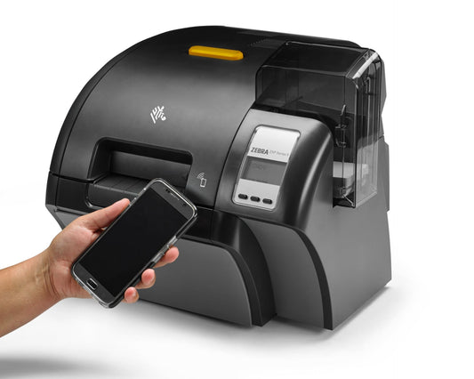 Zebra label printer with a hand holding a smartphone on a white - Zebra ZXP Series 9 Dual-Sided ID Card Printer background
